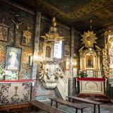 Wnętrze drewnianego kościoła z polichromiami ściennymi, obrazami, amboną.
