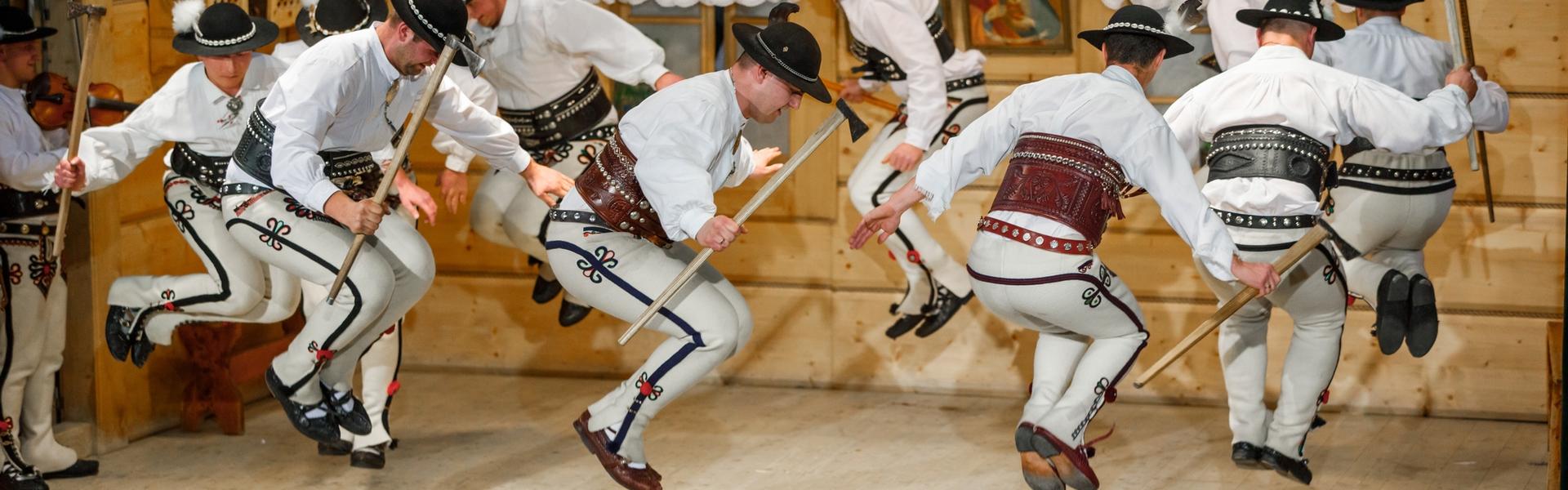 Männer in Goralen-Trachten tanzen mit traditionellen Ciupaga-Axtstöcken. Fasching in Bukowina Tatrzańska