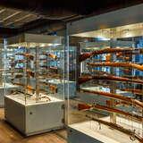 Ustawione w rzędzie szklane gabloty w Muzeum Armii Krajowej w Krakowie ze starą, drewnianą bronią - karabinami.