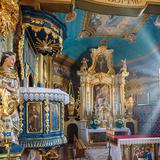 Prezbiterium kościoła. Na pierwszym planie ambona. W tle ołtarz główny z obrazem świętego Mikołaja. Wnętrze bogato zdobione, barokowo-rokokowe w tonacji błękitnej i złotej, polichromowane.