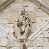 Rzeźba Matki Boskiej z Dzieciątkiem, wykonana w kamieniu, umieszczona we wnęce na kamiennej ścianie.