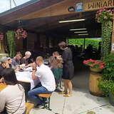Kilkanaście osób przy stołach przed drewnianą wiatą podczas prelekcji i degustacji w Winnicy Zawadka w Tęgoborzu.