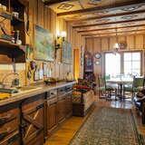 Wnętrze kuchni i jadalni z drewnianymi szafkami , w tle stół z krzesłami i okno