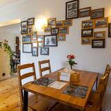 Wnętrze lokalu gastronomicznego, drewniane stoliki i krzesła, na ścianie małe obrazki w drewnianych ramkach